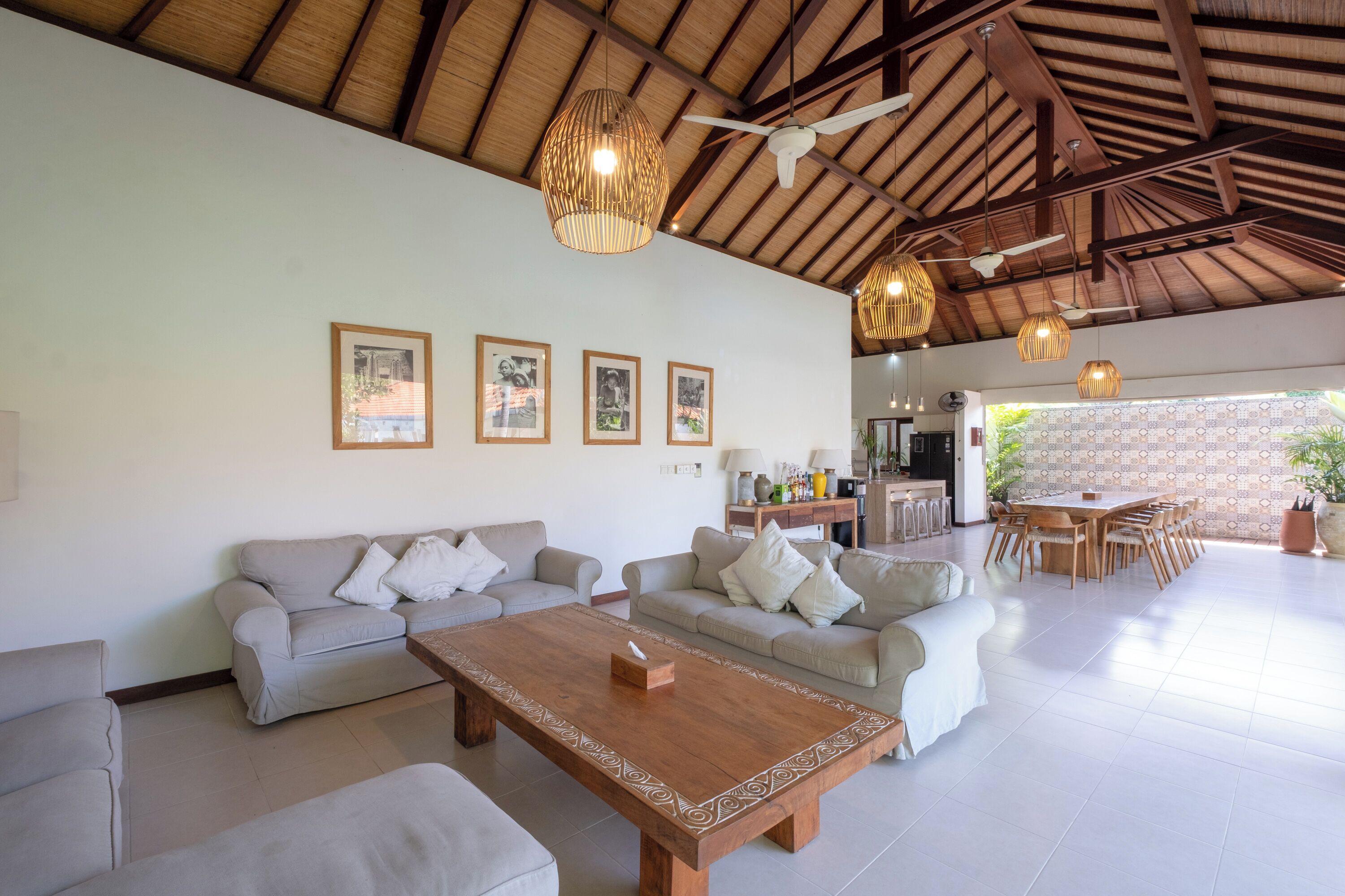 A spacious living area with a high ceiling, wooden beams, and a dining area with a large table and chairs.