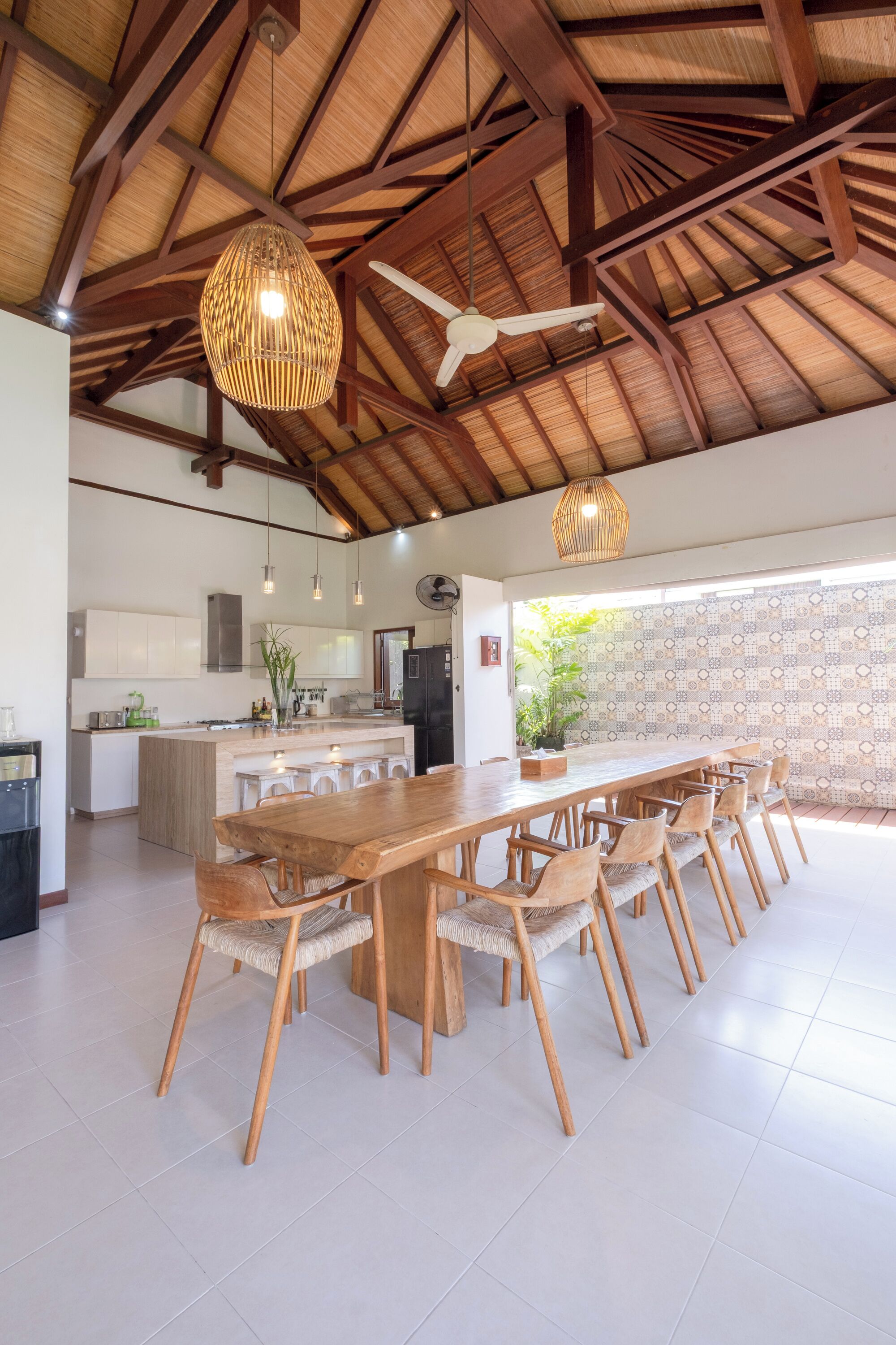 A spacious kitchen with white cabinets, a central island, and a dining area with a long wooden table and chairs.