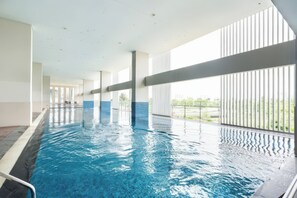 A long indoor swimming pool with clear blue water, surrounded by large windows and a tiled floor. - SECC Scenic Valley District 7 (Ho Chi Minh City)