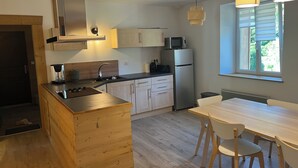 Eine moderne Küche mit einer Holzinsel, Edelstahlgeräten und einem Essbereich mit Tisch und Stühlen.