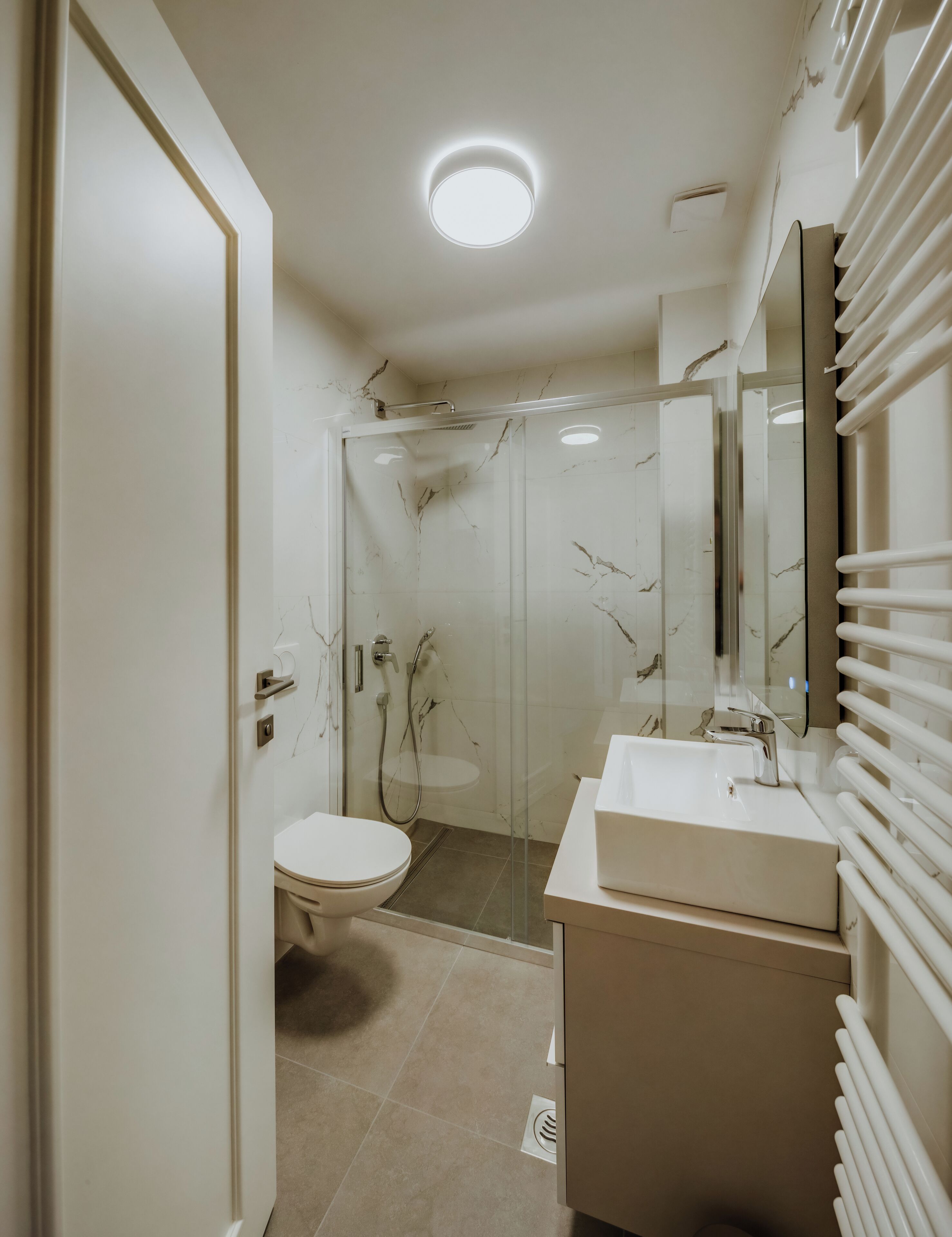 A modern bathroom with a glass shower enclosure, a white sink, and a toilet.