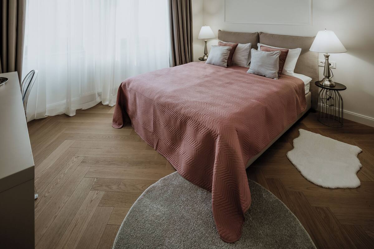 Une chambre à coucher moderne avec un grand lit, un tapis rond, une table de chevet avec une lampe et un luminaire au plafond.