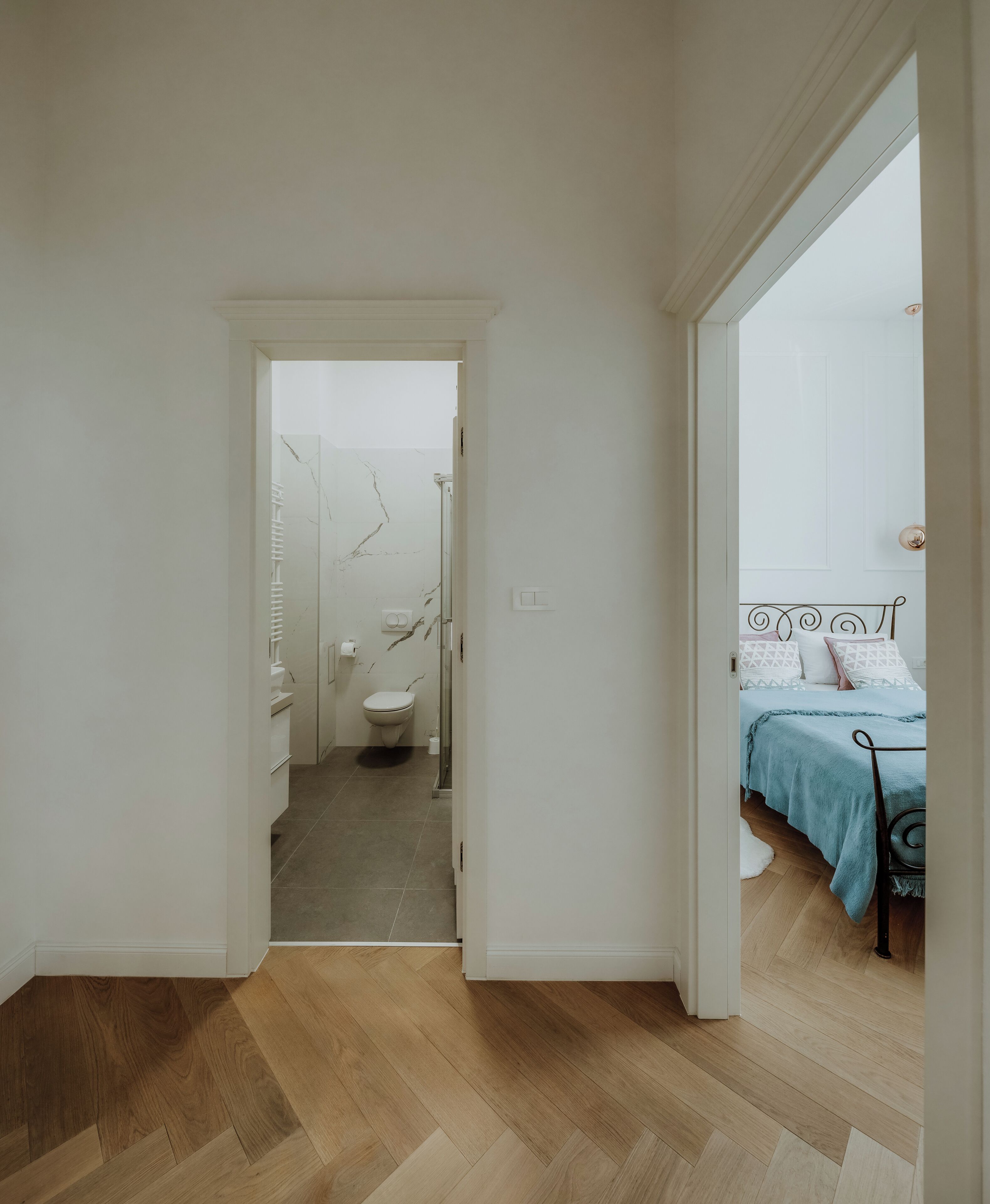 A hallway leading to a bathroom with a toilet and a shower.