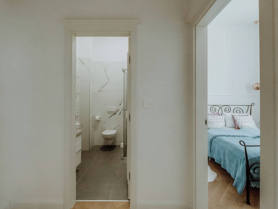 A hallway leading to a bathroom with a toilet and a shower.