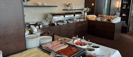 A buffet setup with various food items, including meats, cheeses, and condiments, arranged on a table with a white tablecloth.