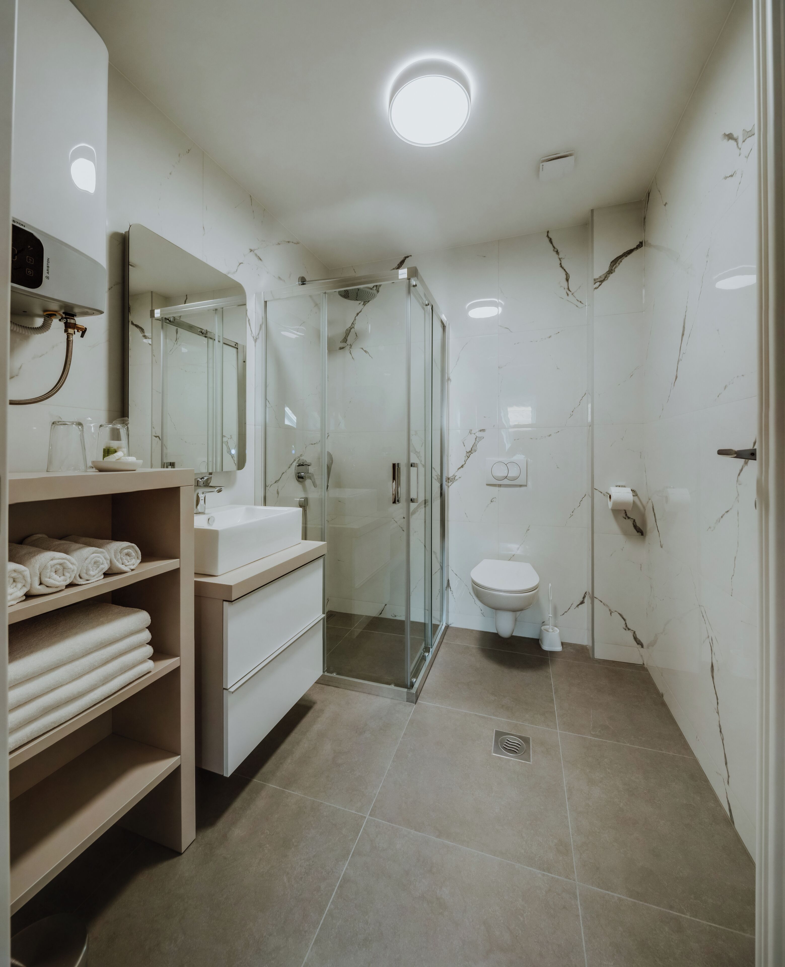 A modern bathroom with a glass-enclosed shower, a white sink, and a toilet.