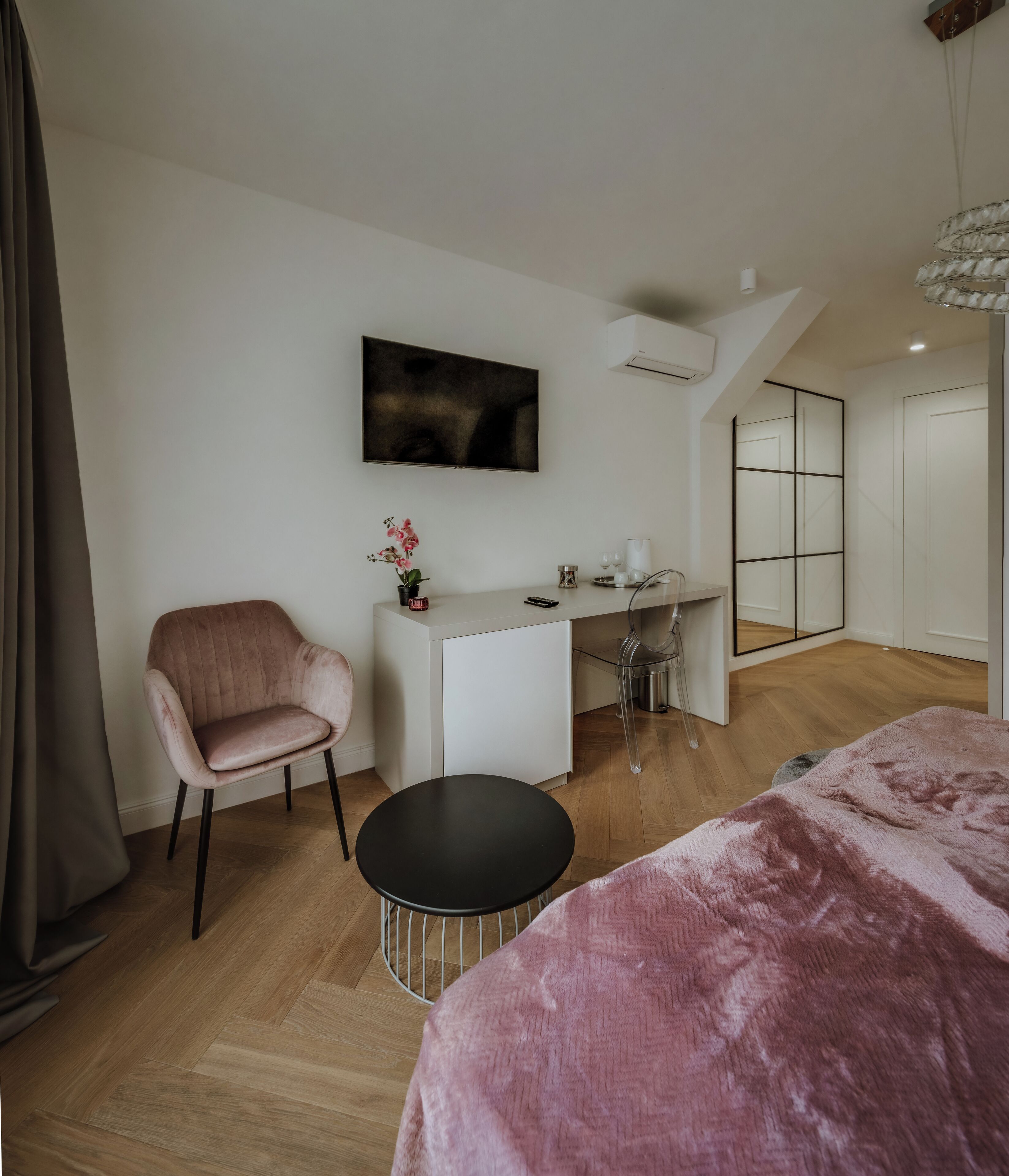 Un dormitorio moderno con una cama, un escritorio, una silla y un televisor.