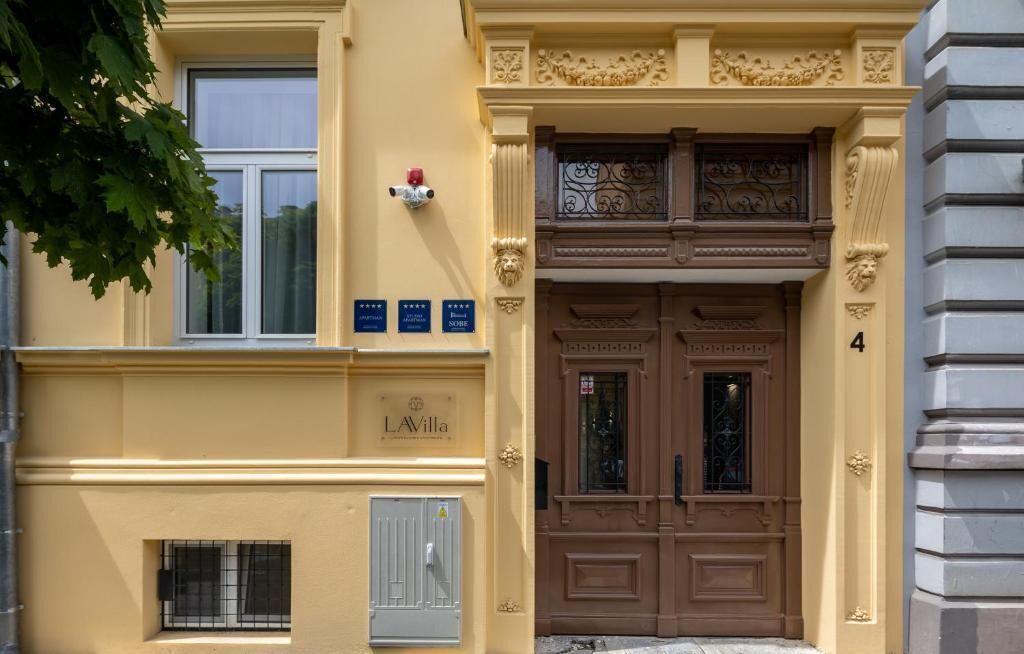 Fachada de edificio con entrada de doble puerta, un letrero que dice 'LAVilla' y una placa con premios.