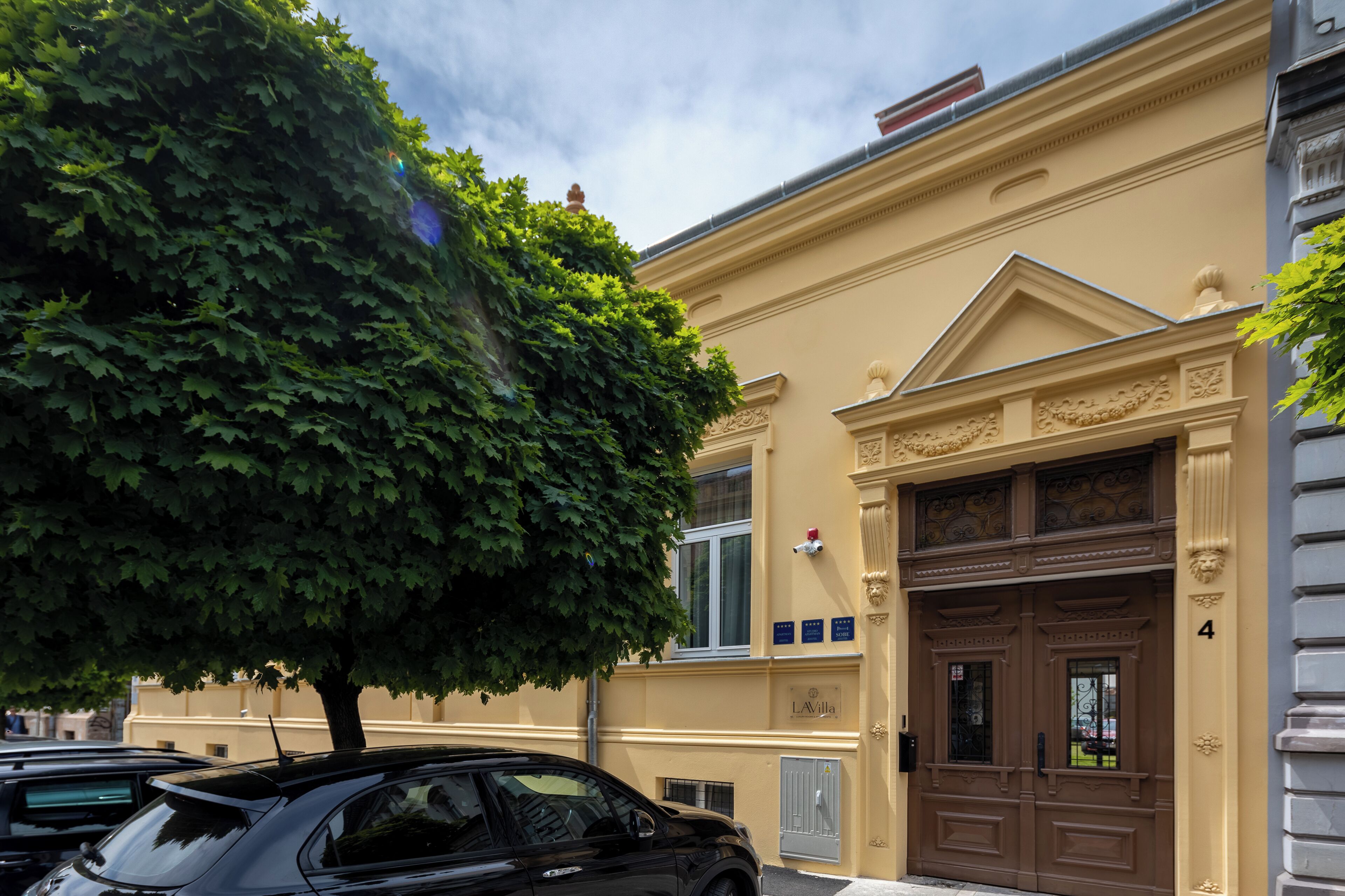 A building with a large tree in front, a double door entrance, and a number '4' on the side.
