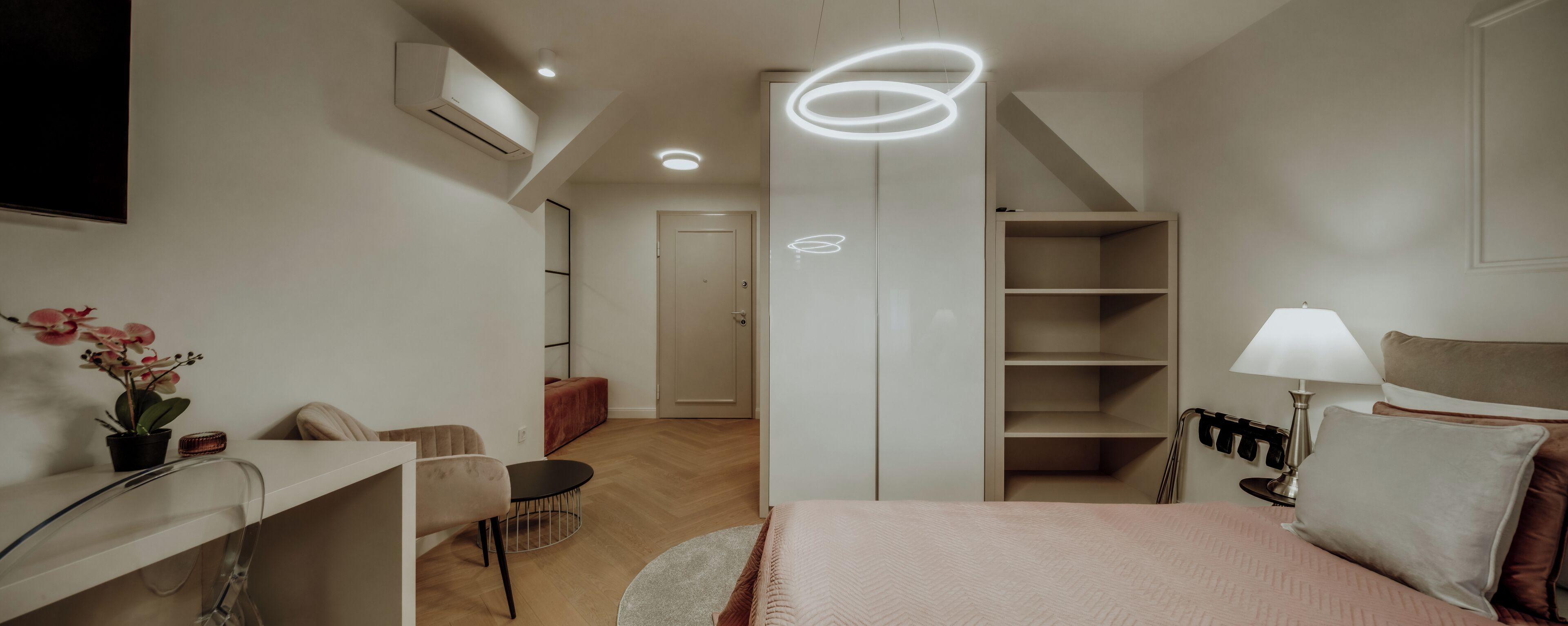 Un dormitorio moderno con cama, mesita de noche, lámpara y armario.