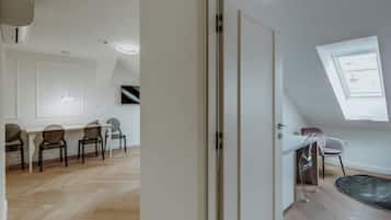 A spacious room with a wooden herringbone floor, a white door, and a skylight.