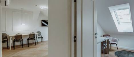 Una habitación amplia con suelo de madera en patrón de espiga, una puerta blanca y un tragaluz.