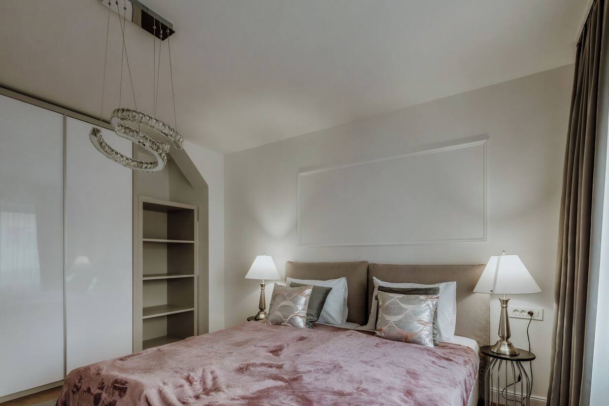 Une chambre à coucher avec un grand lit, deux tables de chevet avec des lampes, une armoire et un luminaire au plafond.