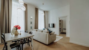 A modern living room with a sofa, dining table, and TV. - LAVilla Osijek (Osijek)