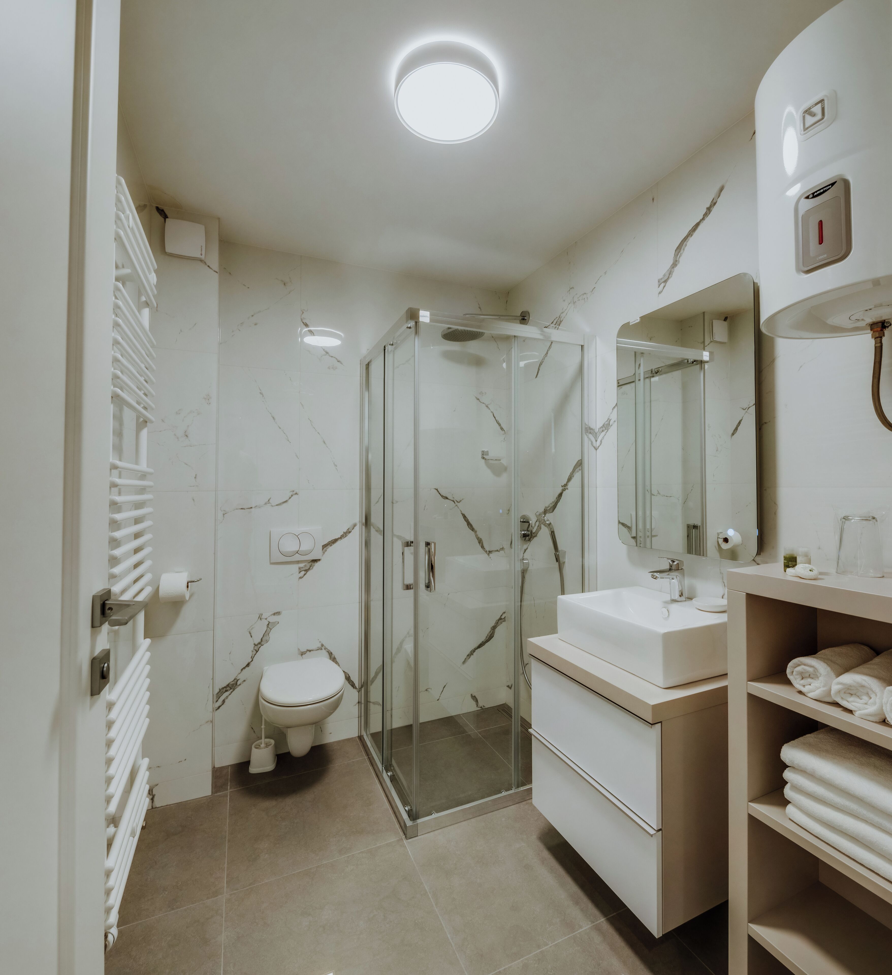 A modern bathroom with a glass-enclosed shower, a toilet, and a vanity with a sink and mirror.