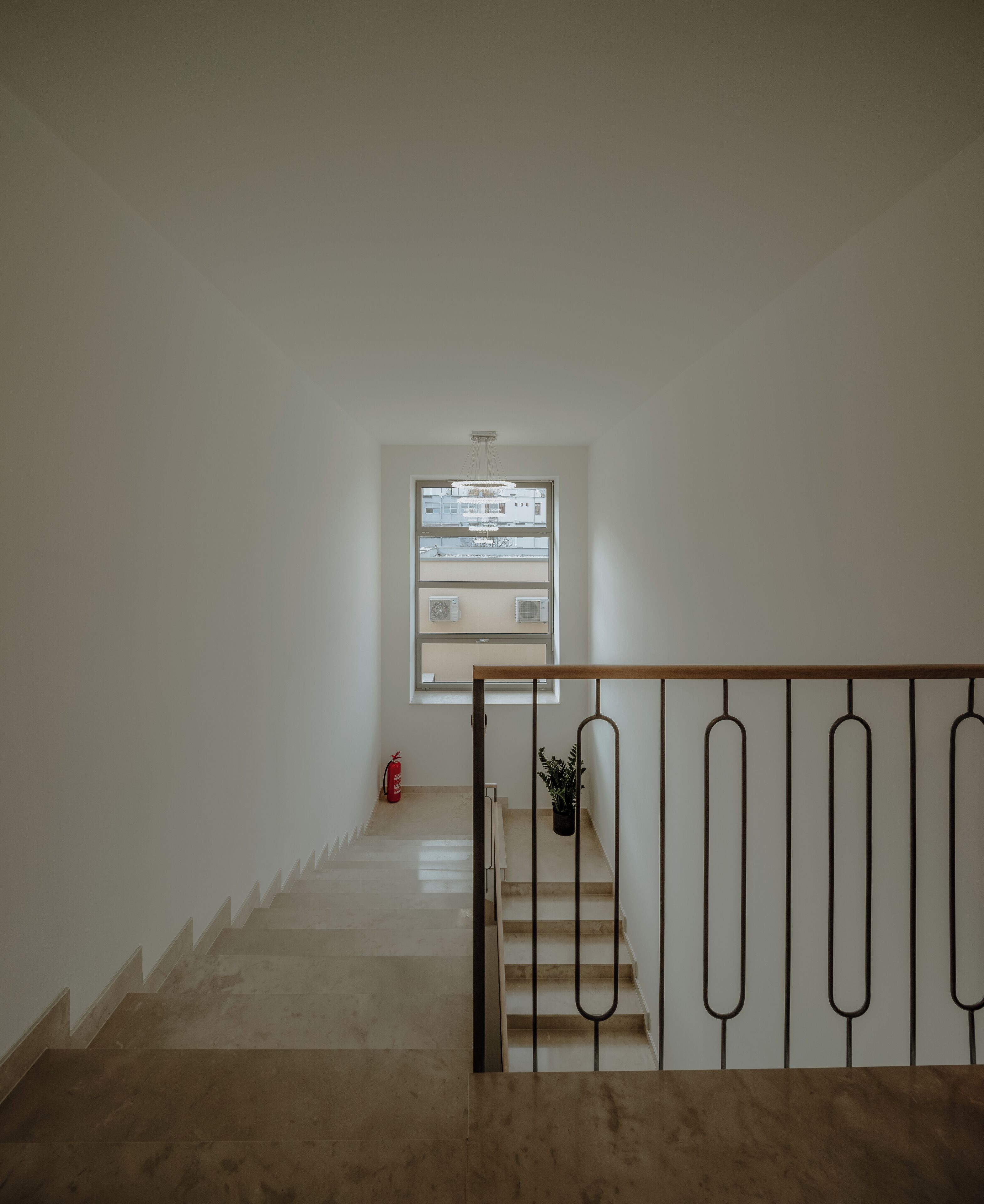 Una escalera que lleva a una plataforma con una ventana, un extintor y una planta en maceta.
