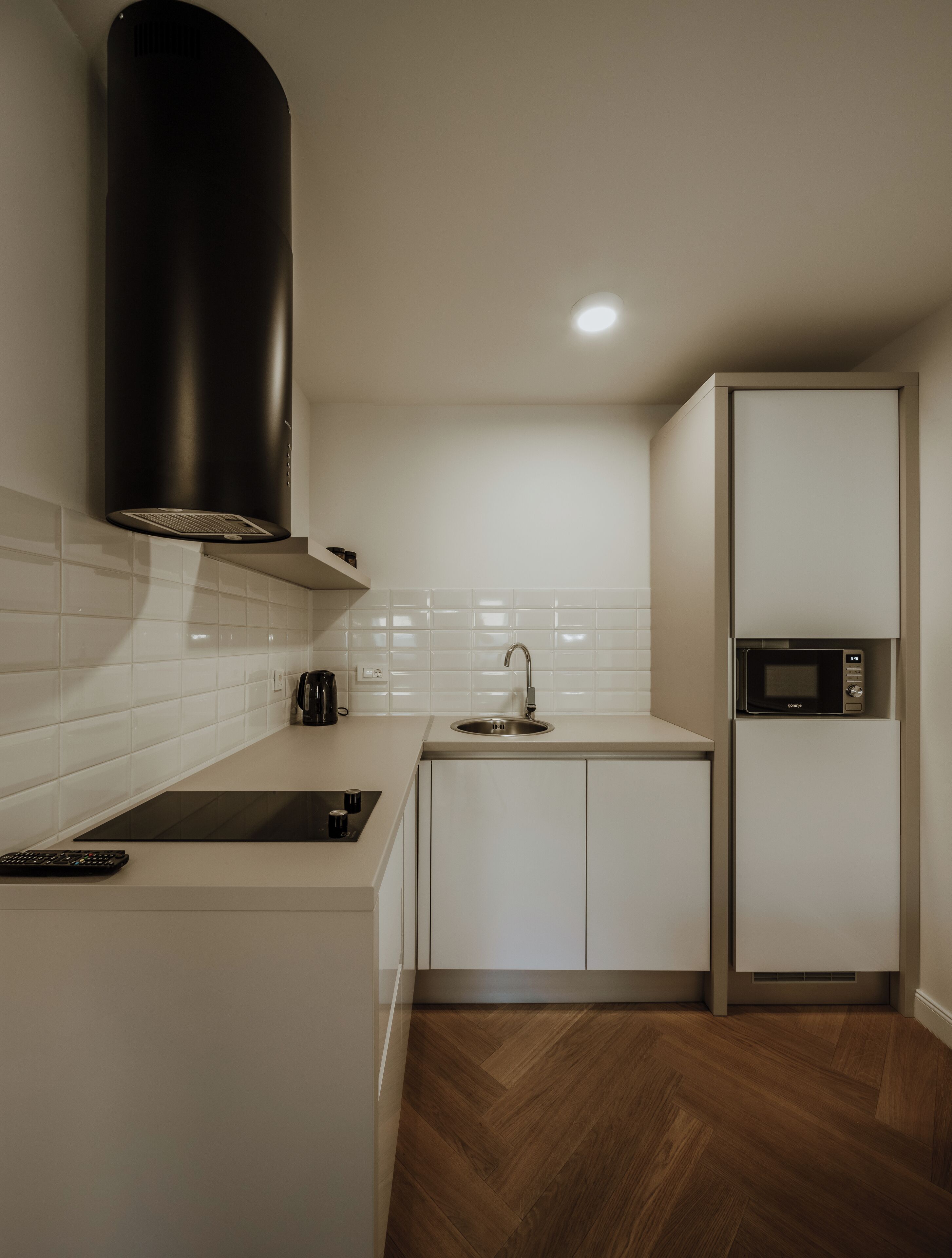 A compact kitchen with a black range hood, a built-in microwave, and a sink.