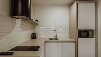 A compact kitchen with a black range hood, a built-in microwave, and a sink.