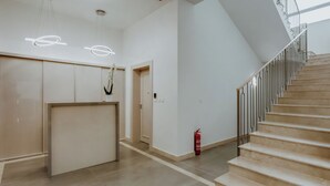 A spacious, modern interior with a staircase leading to a balcony, minimalist design, and a fire extinguisher near the stairs. - LAVilla Osijek (Osijek)