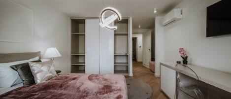 Un dormitorio moderno con cama, mesita de noche, lámpara y un amplio armario.