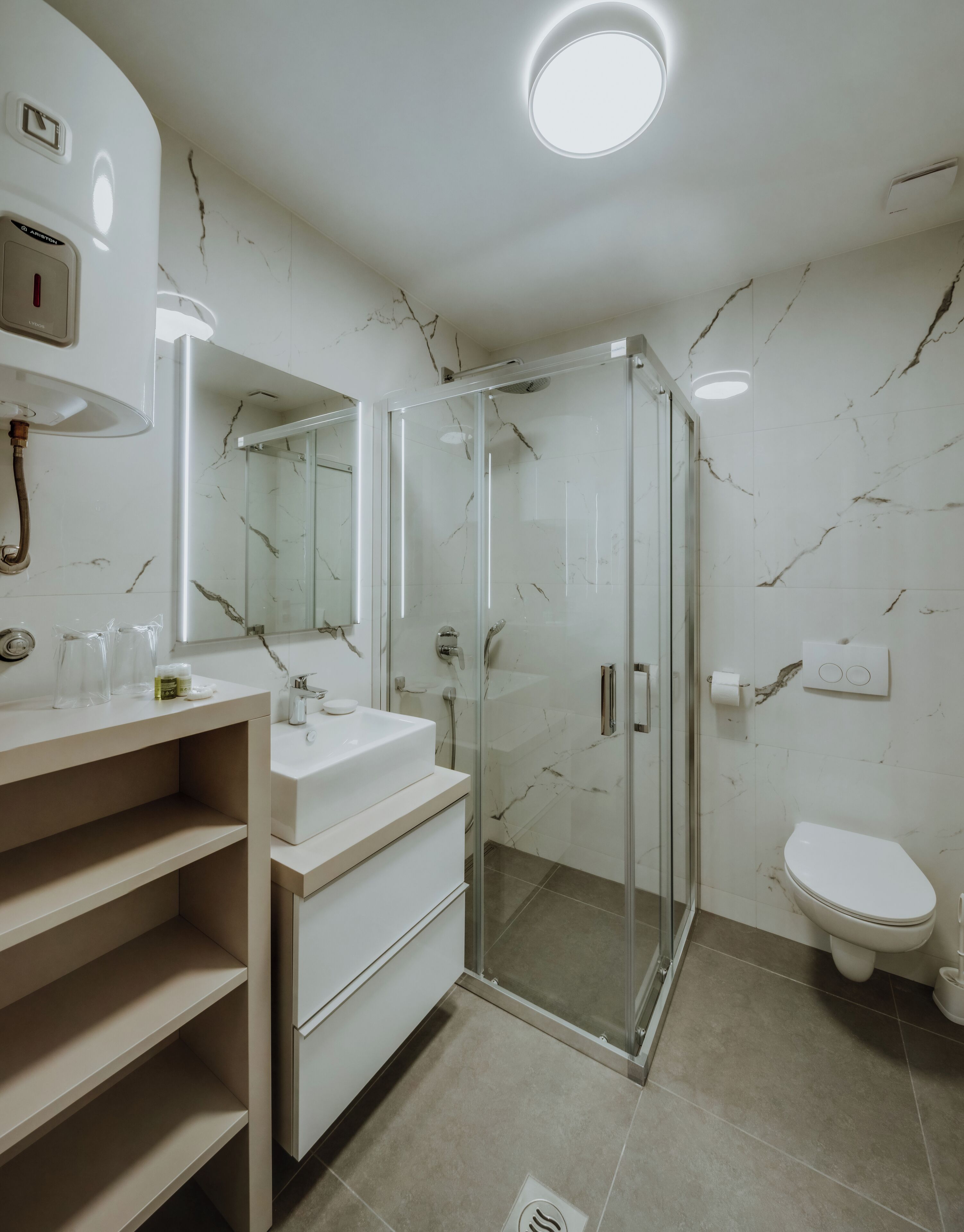 Een moderne badkamer met een douchecabine van glas, een witte wastafel met spiegel en een toilet.