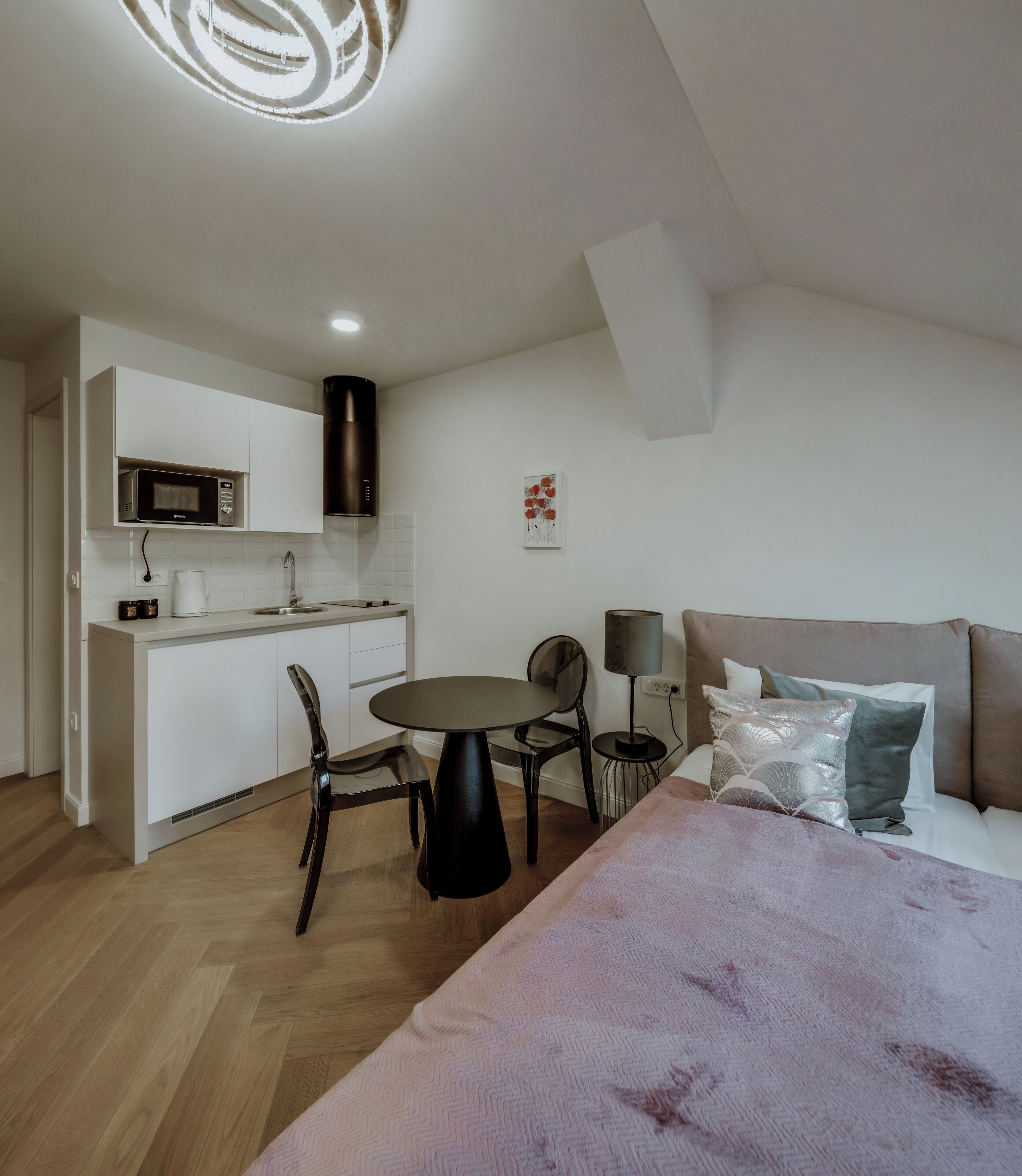 Ein modernes, kompaktes Zimmer mit Küchenzeile, Essecke und Bett.