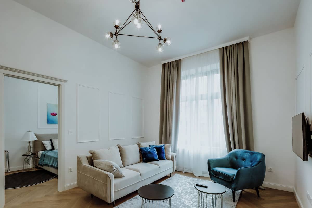 Un salon moderne avec un canapé, un fauteuil bleu, une table basse et un lustre.