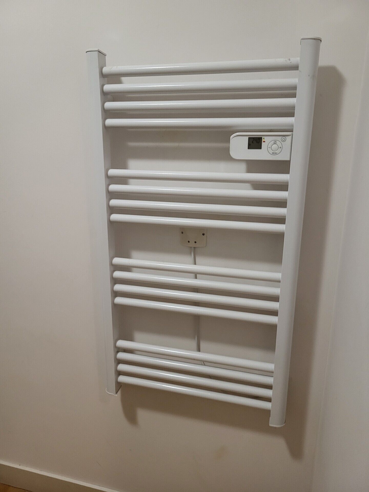 Un radiador blanco fijado a la pared con termostato digital.