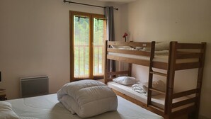 A bunk bed room with a window, a radiator, and a bedside table.