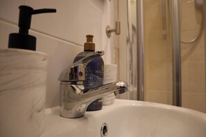 A bathroom sink with a chrome faucet, a soap dispenser, and a toilet paper holder.