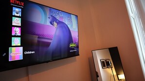 Un téléviseur fixé au mur affiche un personnage de dessin animé et l’interface de Netflix.