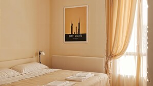 A hotel room with a bed, a headboard, a bedside lamp, and a window with curtains. - cinecittaroomshaven (Rome)