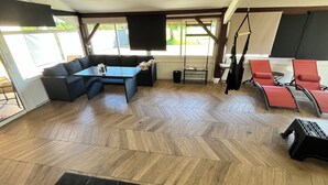 Een kamer met een visgraatmotief houten vloer, een bank, een tafel en een schommelstoel.