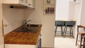 A kitchen with a wooden countertop, a sink, and a shelf with spices. There is a dining area with chairs and a table. - 170m2 with private garden (Wien)