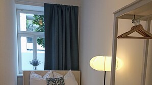 A compact bedroom with a bed, a chair, a bedside table, a lamp, and a window with curtains. - 170m2 with private garden (Wien)