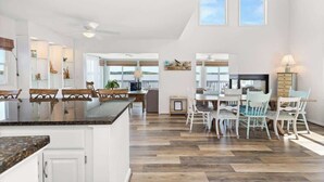 A spacious kitchen with a large island, wooden flooring, and white cabinetry. - Dolphins Chance - Waterfront Ocean Pines + Dock (Ocean Pines)