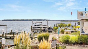 A waterfront property with docked boats, a flag, and a view of the water. - Dolphins Chance - Waterfront Ocean Pines + Dock (Ocean Pines)