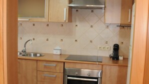 Una cocina con armarios de madera, un horno de acero inoxidable, un lavamanos y una lámpara colgante.