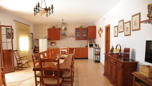 Una cocina amplia con armarios de madera, una mesa de comedor con sillas y un candelabro.