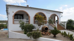 Un edificio blanco con tres ventanas de arco y una escalera que lleva a la entrada.