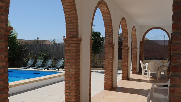 Un espacio al aire libre cubierto con piscina, sillas de descanso y vistas al paisaje.