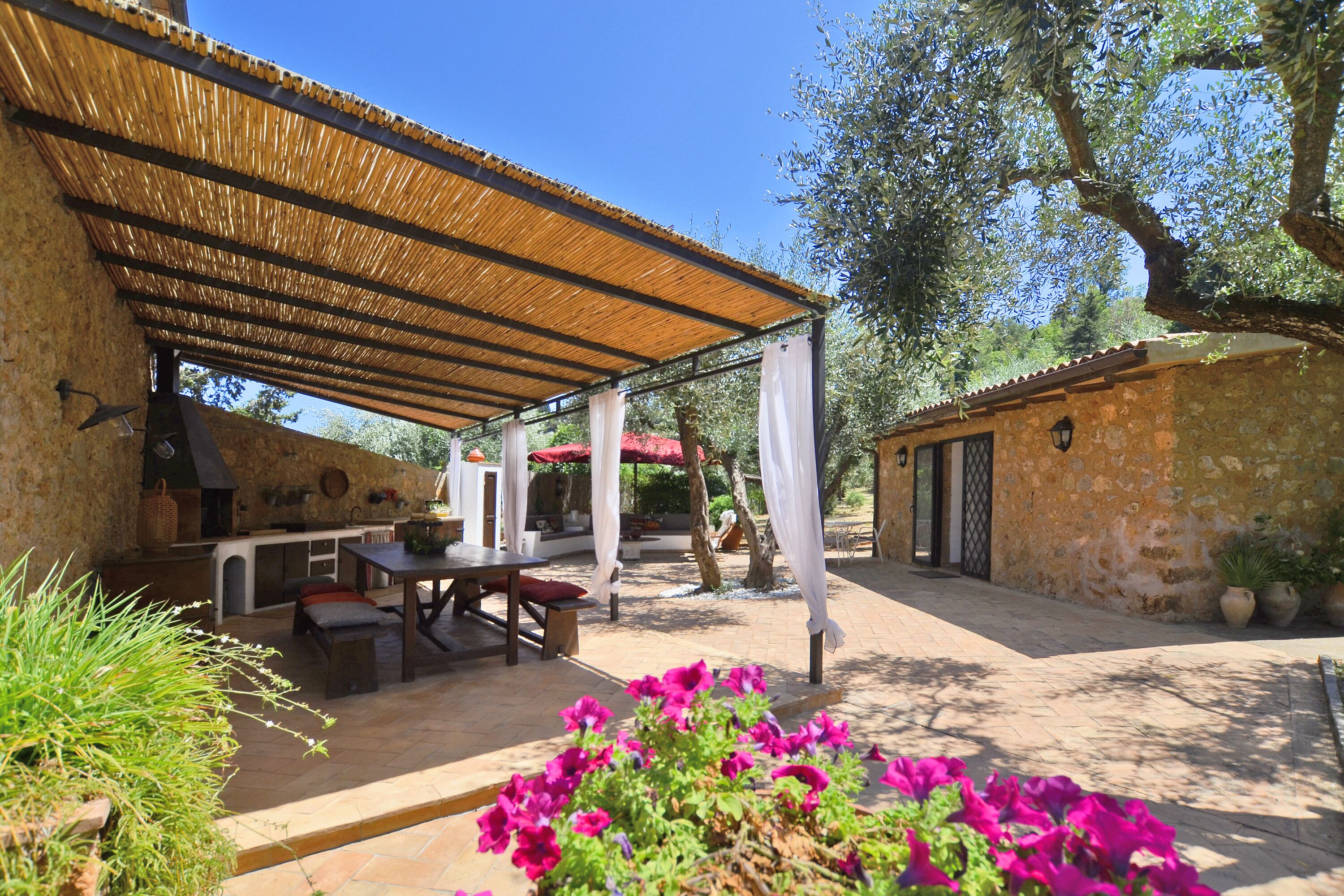 An outdoor patio with a covered seating area, stone walls, and potted plants.