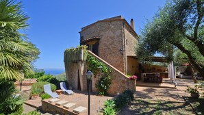Un bâtiment en pierre doté d’un patio, d’un espace extérieur aménagé pour s’asseoir et offrant une vue sur la mer.