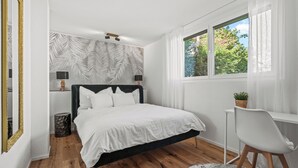 Una camera da letto con un letto, una scrivania, una sedia, una finestra e una parete decorata con un motivo a foglia.