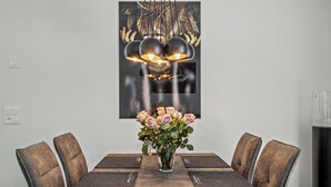 Un tavolo da pranzo con sei sedie, un vaso di fiori e un lampadario moderno.