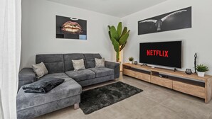Un soggiorno moderno con un divano ad angolo grigio, una TV a schermo piatto e opere d'arte alle pareti.