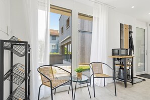 A modern living room with a glass table, two wicker chairs, a television, and a small potted plant.