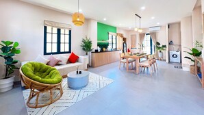 A modern living room with a sofa, a dining table, and a kitchen area. - Kim Sa Village - NovaWorld Phan Thiet (Tien Thanh)
