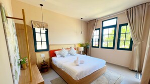A bedroom with a wooden bed, a bedside table, a mirror, and a window with curtains. - Kim Sa Village - NovaWorld Phan Thiet (Tien Thanh)