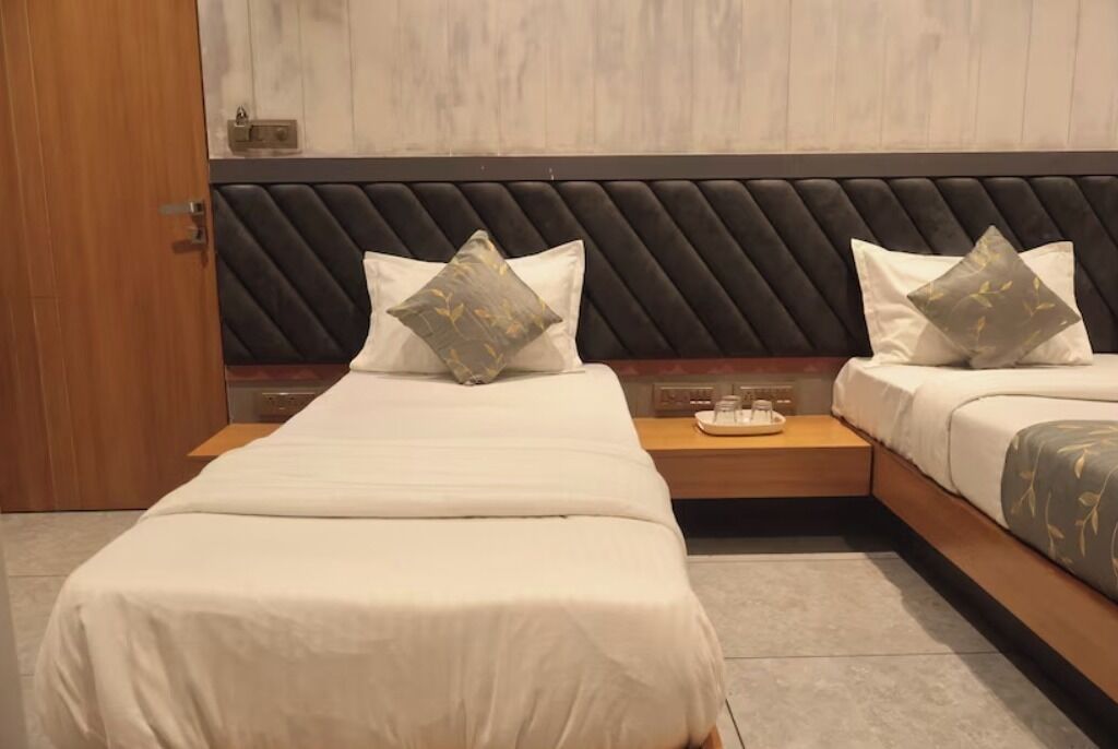 A hotel room with a modern design, featuring a large bed with a black upholstered headboard, two bedside tables, and a wooden nightstand.